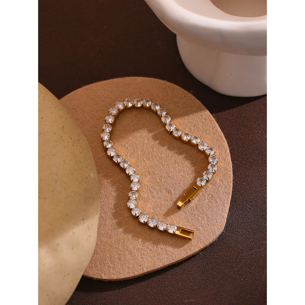 Bracelet tennis avec zircons, doré, sur une surface claire – Charmhabit