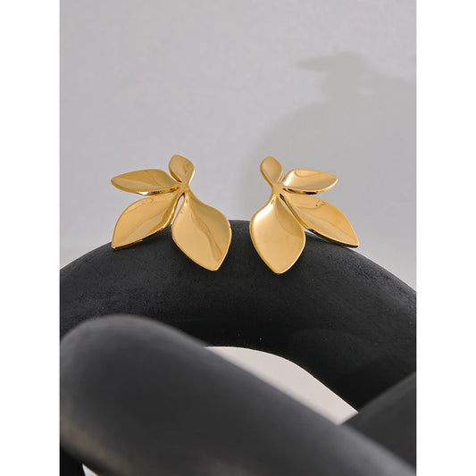 Blatt-Ohrstecker in Goldfarben auf dunklem Stoff – Charmhabit