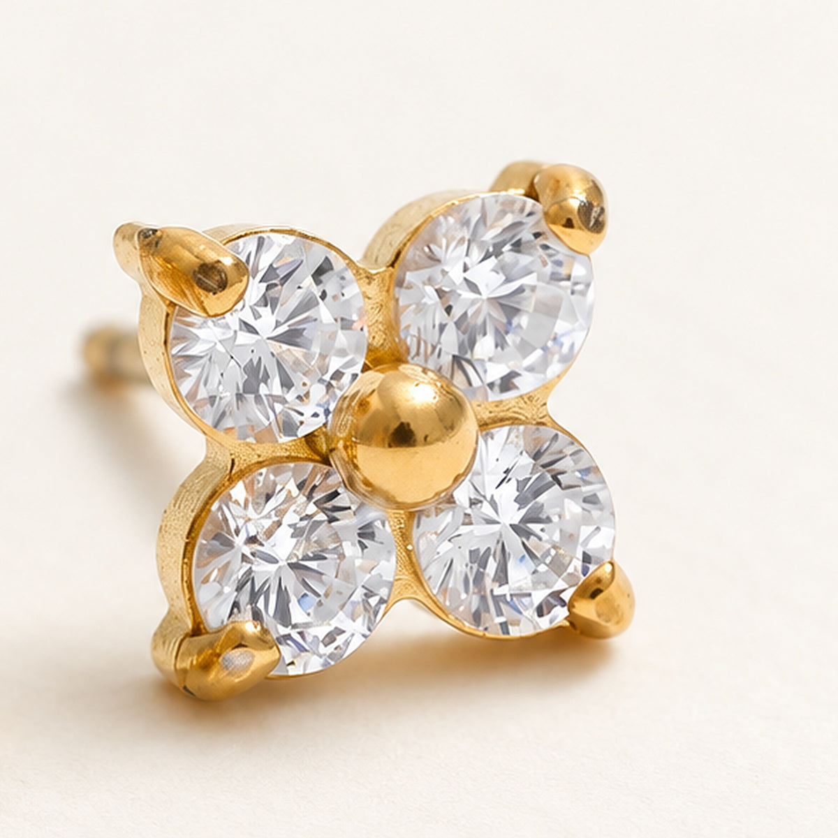 Close-up of a flower stud earring, gold tone, with four clear stones – Charmhabit