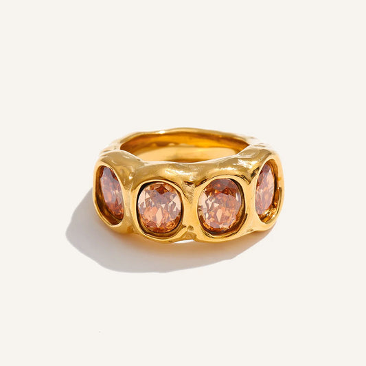 Wide ring with champagne-coloured cubic zirconia, gold tone, on a light background – Charmhabit