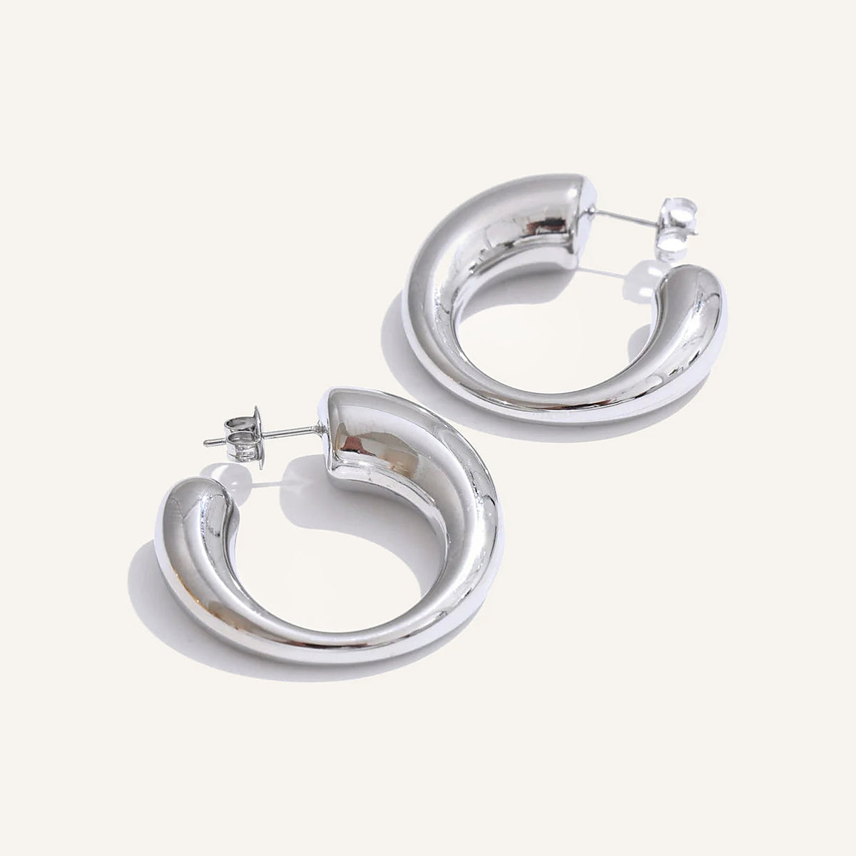 Chunky C-shaped hoop earrings in silver tone, on a light background – Charmhabit