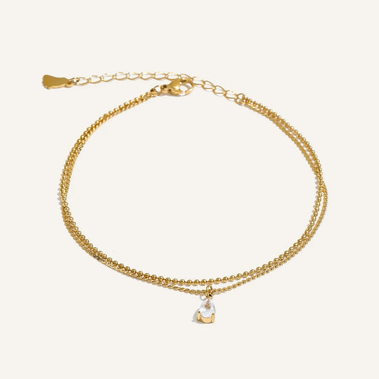 Double anklet with cubic zirconia drop, gold tone, on a light background – Charmhabit
