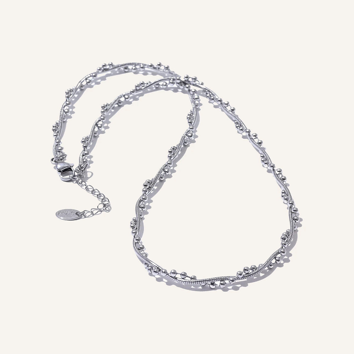 Gedraaide ketting met bolletjes, zilver, op een lichte achtergrond – Charmhabit