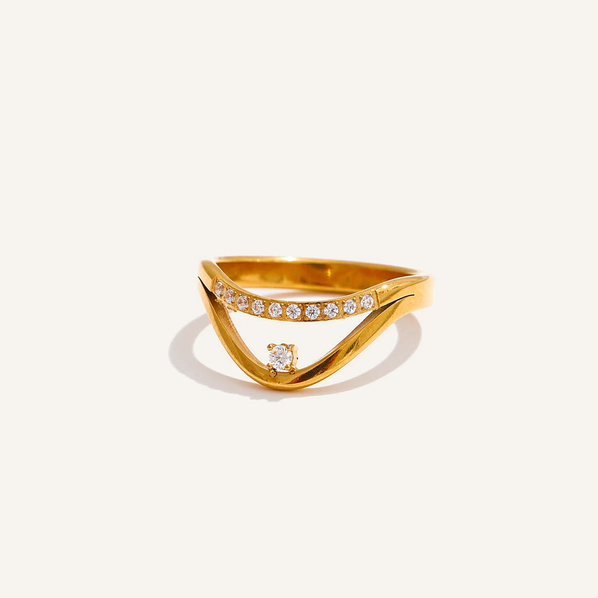 Goldfarbener Ring mit Zirkonia, Wellenband, auf hellem Hintergrund – Charmhabit
