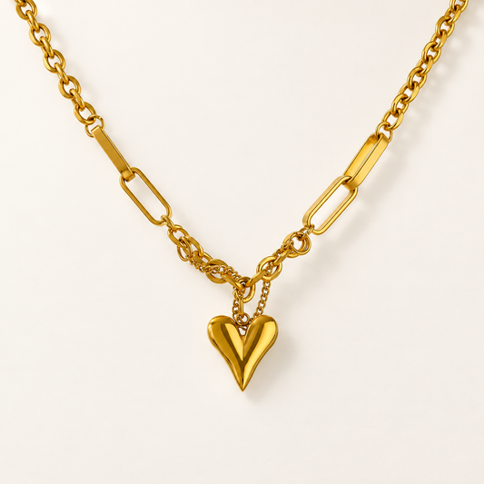 Goudkleurige ketting met hartvormige hanger op een rustige ivoorkleurige achtergrond