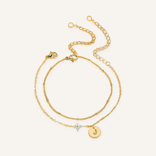 Klaverarmband met initiaal, dubbele goudkleurige armband, op een lichte achtergrond – Charmhabit