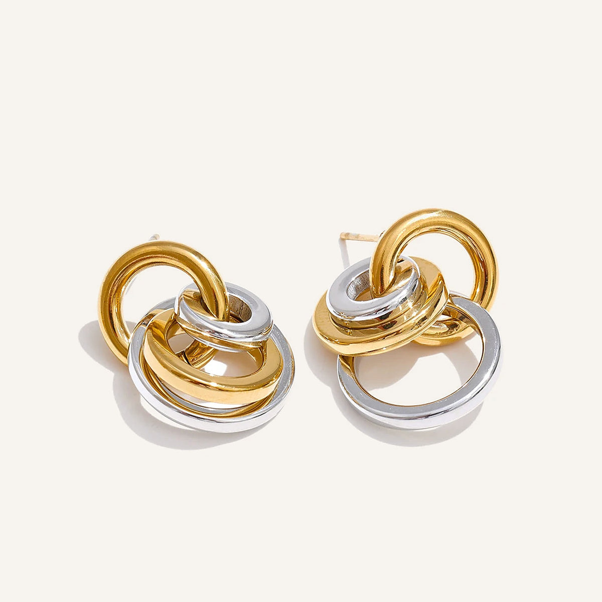 Interlaced circle stud earrings, gold tone and silver tone, on a light background – Charmhabit