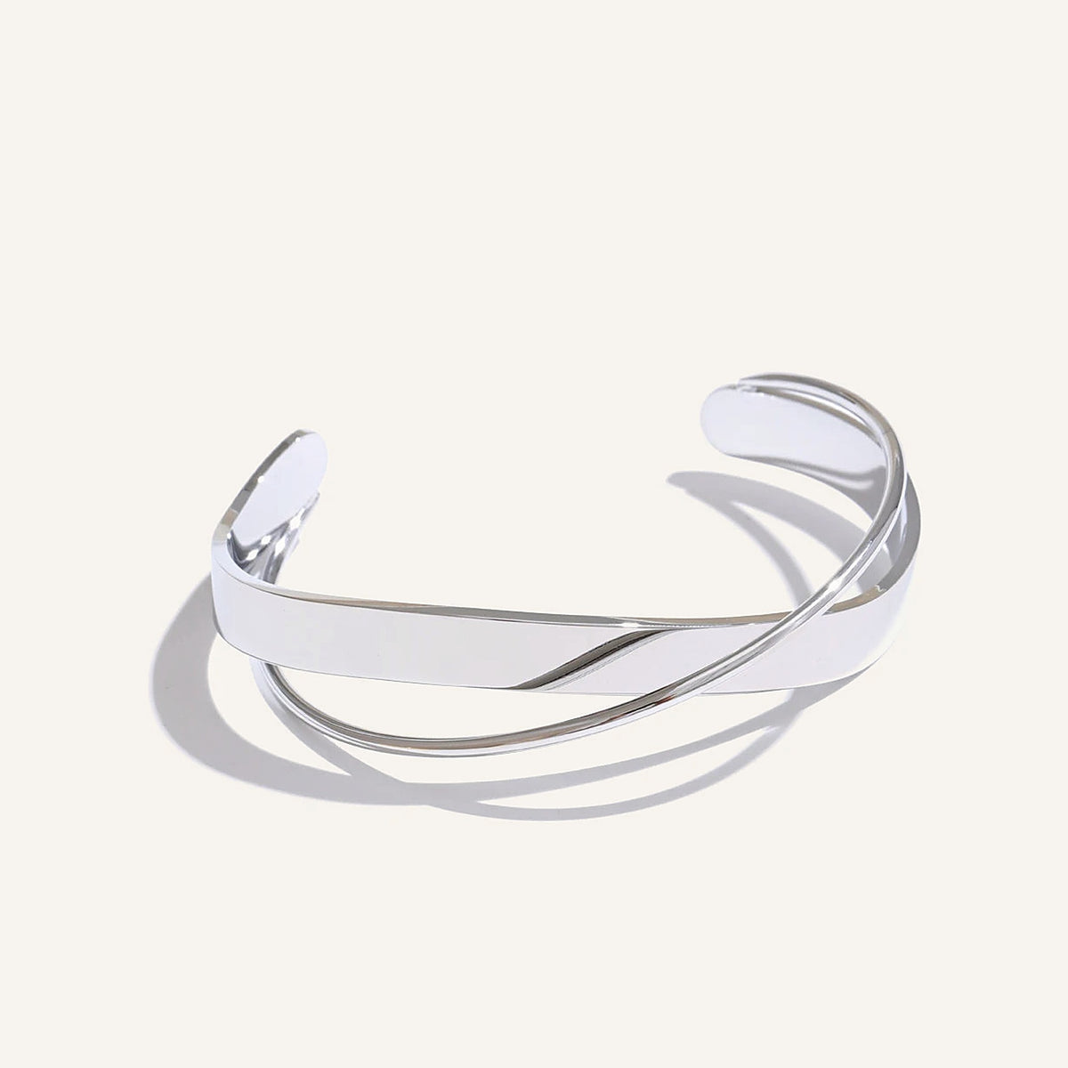 Open armband met gekruiste banden, zilver, op een lichte achtergrond – Charmhabit