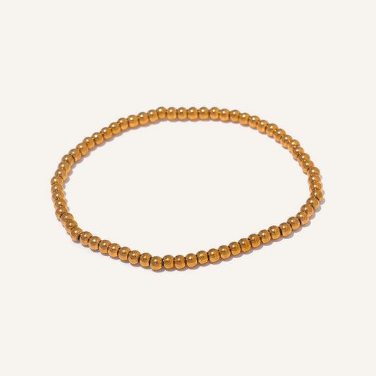Stretcharmband mit Edelstahlkugeln, goldfarben 3 mm, auf hellem Hintergrund – Charmhabit