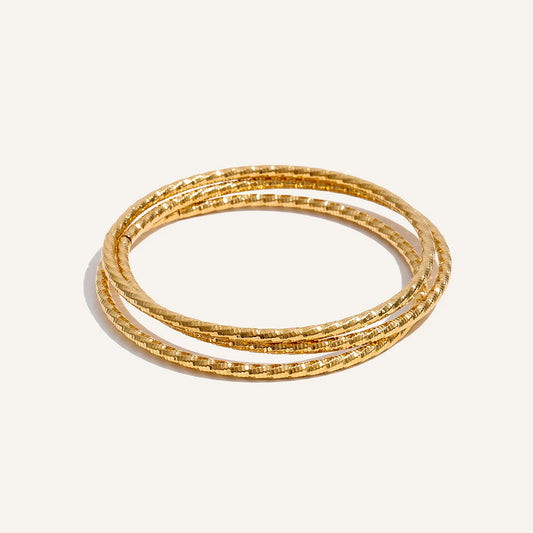 Set of three twisted bracelets, gold tone, on a light background – Charmhabit