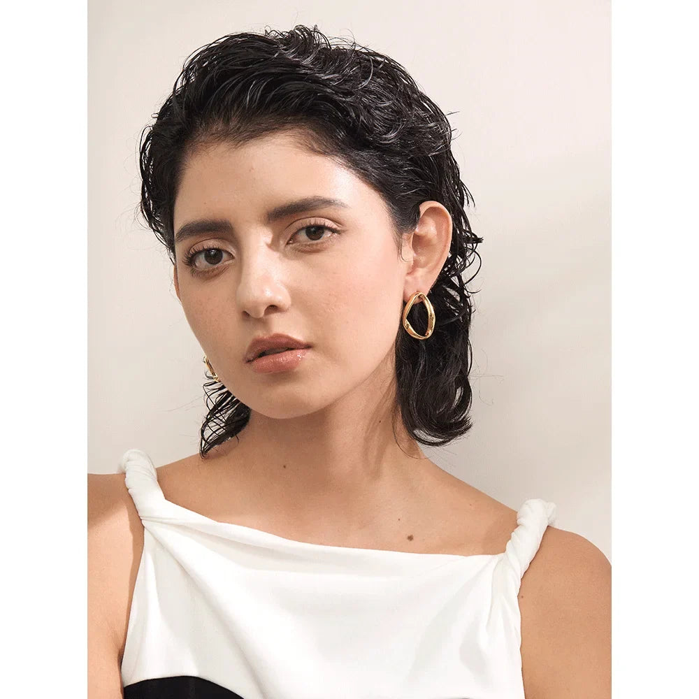 Open oval stud earrings in gold tone, worn