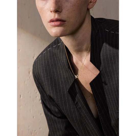 Collier papillon doré avec zircone porté avec un blazer
