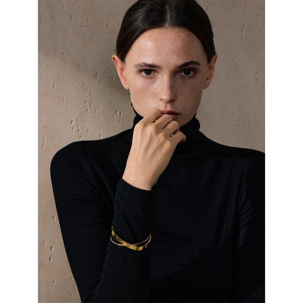 Open armband met gekruiste banden, gedragen met een hand bij het gezicht – Charmhabit