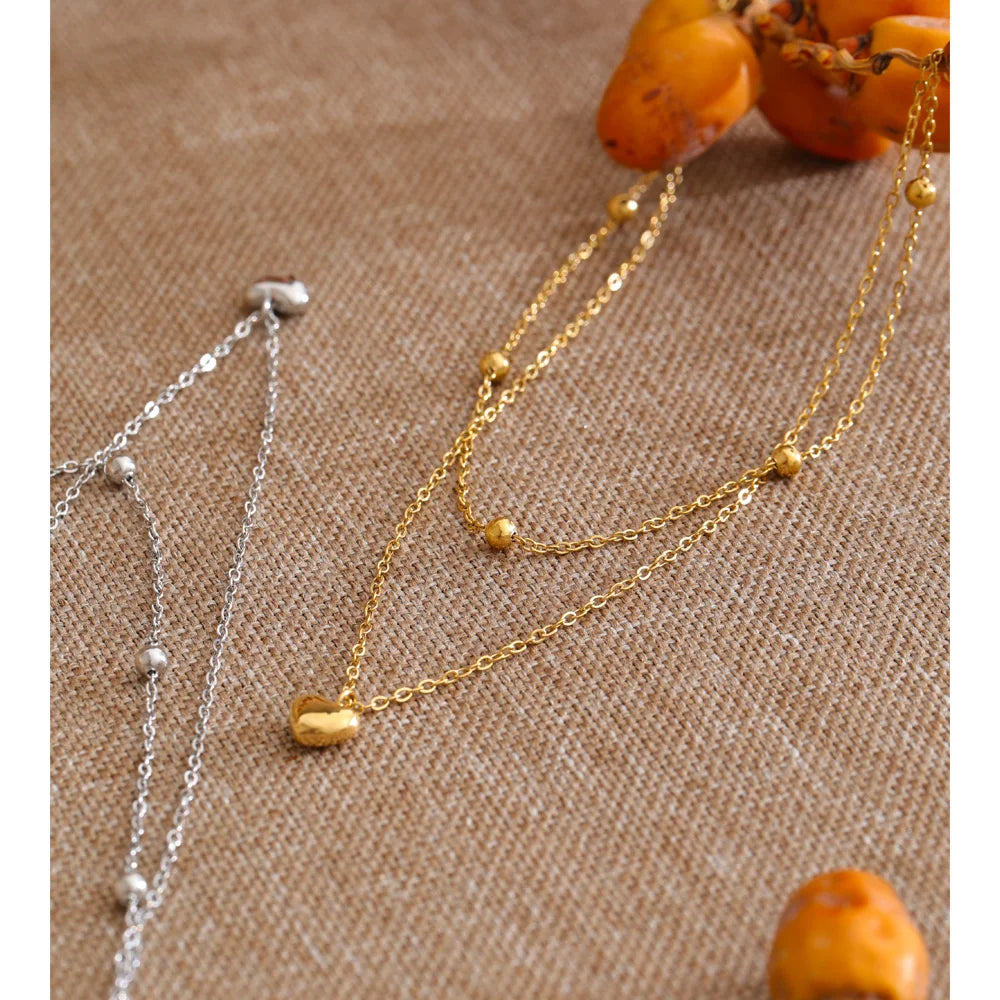 Dubbele ketting met hartjes, goud en zilver, op een linnen doek – Charmhabit