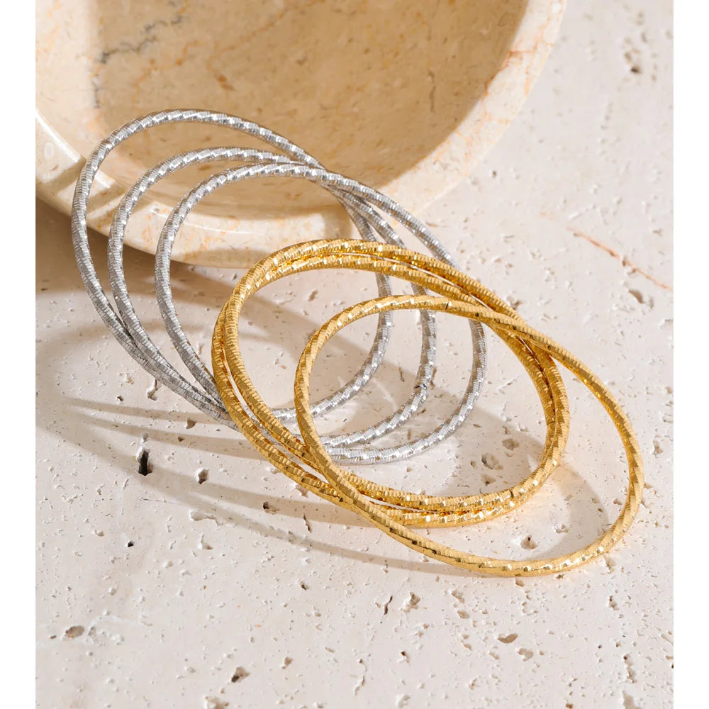 Set aus drei gedrehten Armbändern, Gold und Silber, auf Stein – Charmhabit