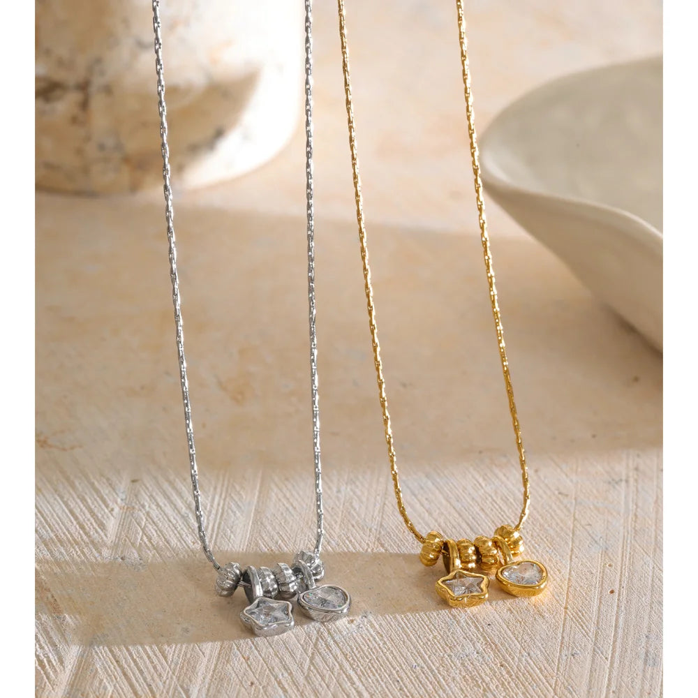 Necklace with heart and star charms, gold and silver tone, on a light surface – Charmhabit
