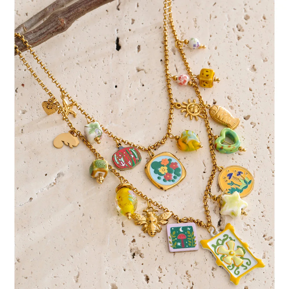 Collier superposé avec breloques colorées, doré, suspendu à une branche – Charmhabit