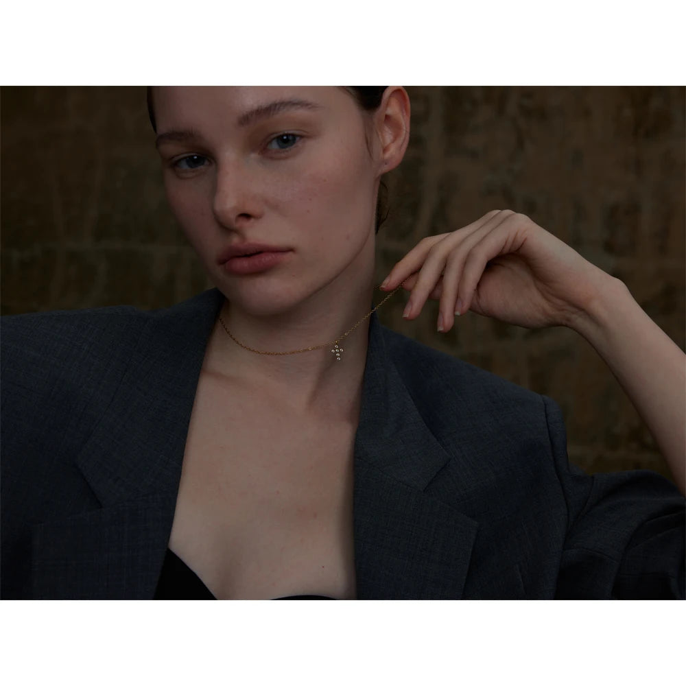 Necklace with cross and zirconia, worn with a hand at the face – Charmhabit