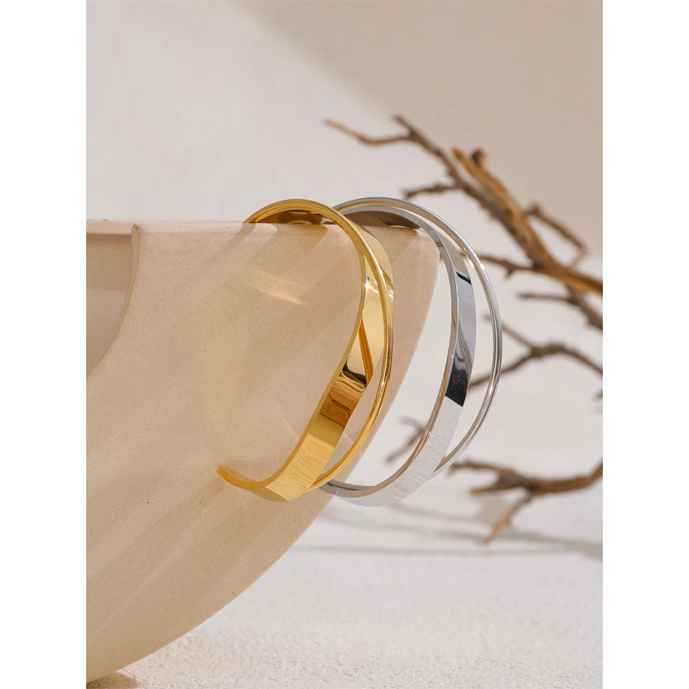 Open armband met gekruiste banden, goud en zilver, aan een tak – Charmhabit