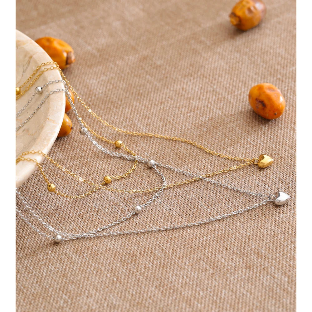 Dubbele ketting met hartjes, goud en zilver, op een linnen doek – Charmhabit