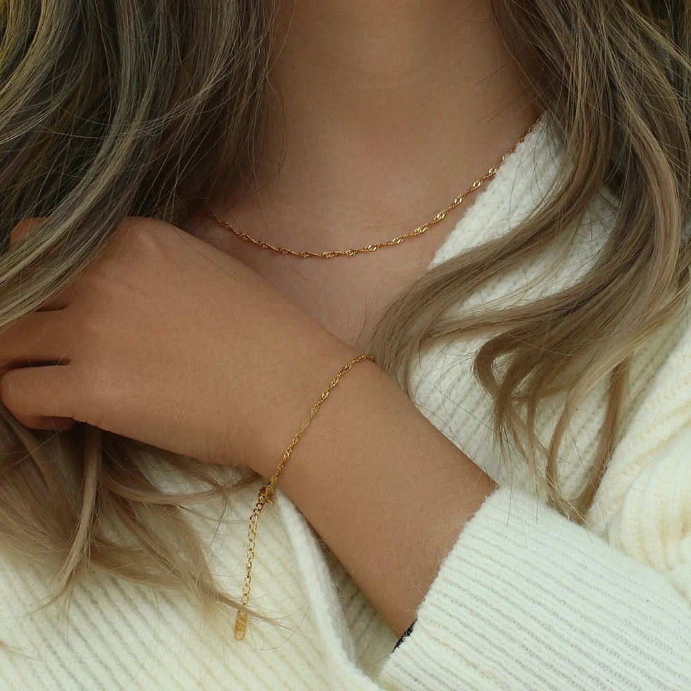 Bracelet et collier Waterwave, dorés, portés avec un pull blanc – Charmhabit