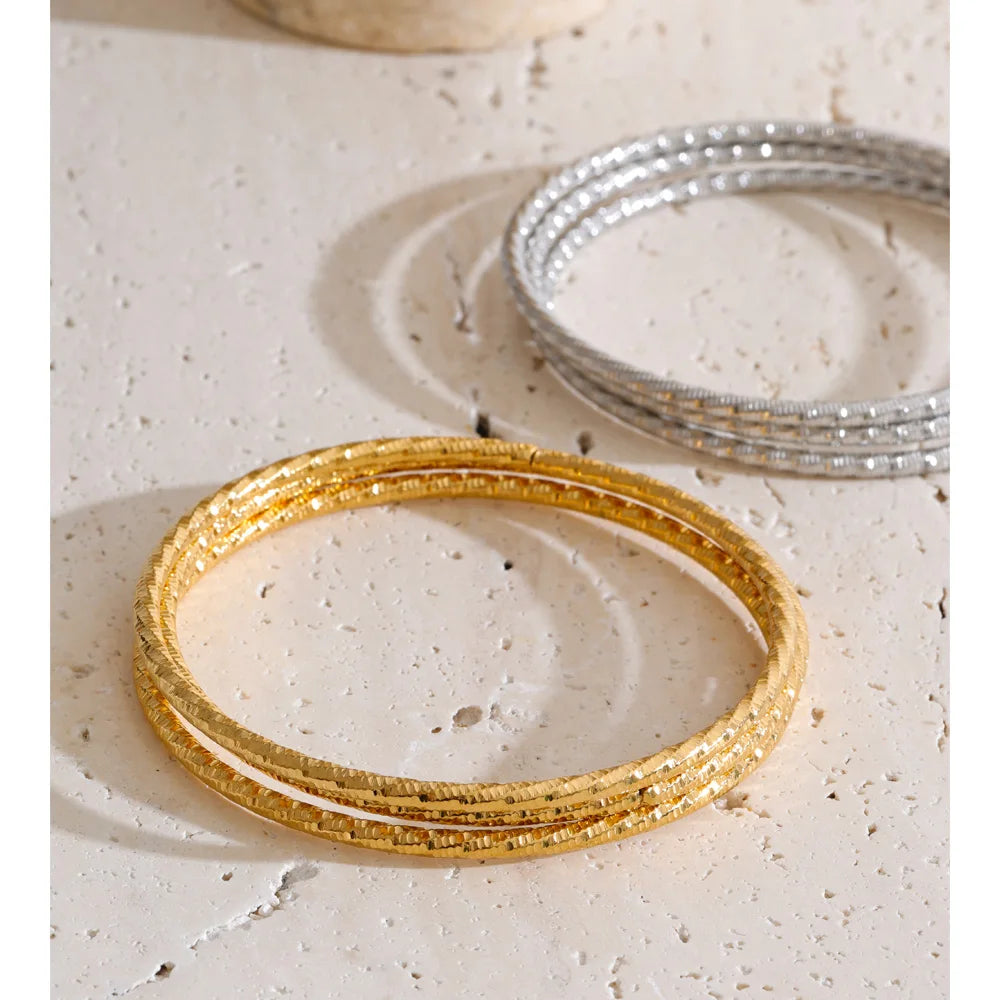Set aus drei gedrehten Armbändern, Gold und Silber, auf Stein – Charmhabit