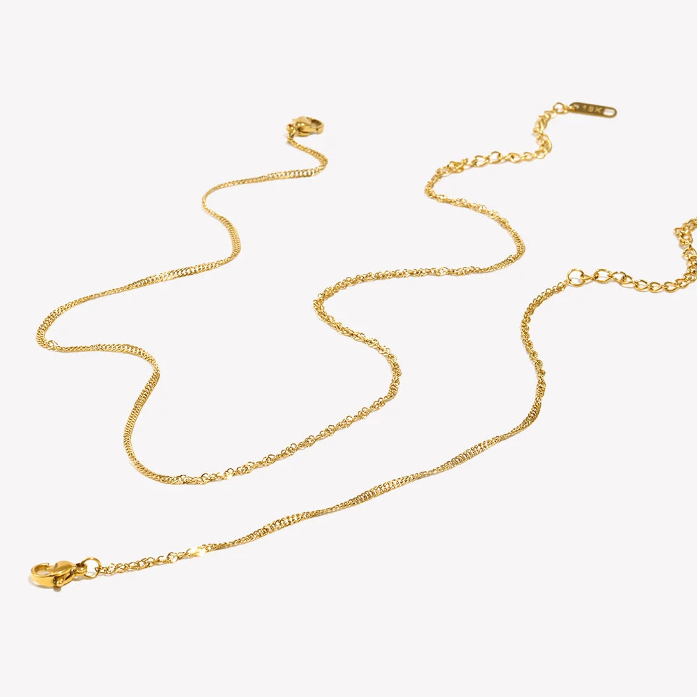 Parure composée d’un fin collier waterwave et d’un bracelet, dorée, sur fond clair – Charmhabit