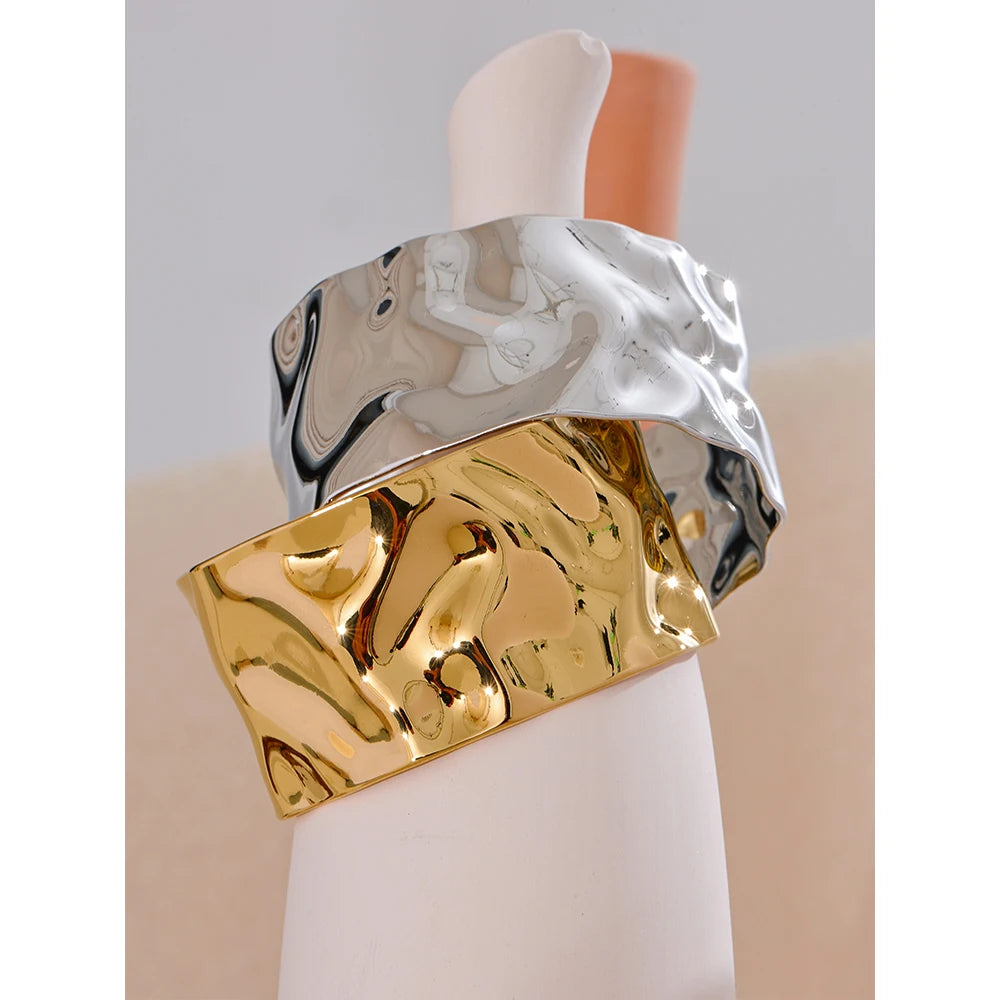 Wide hammered cuff bracelet, gold and silver tone, on a light surface – Charmhabit