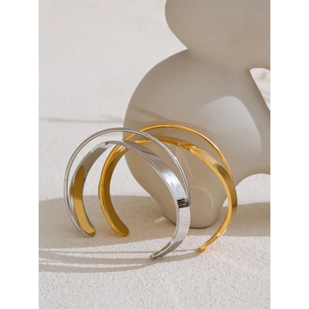 Open armband met gekruiste banden, goud en zilver, op een keramische vorm – Charmhabit