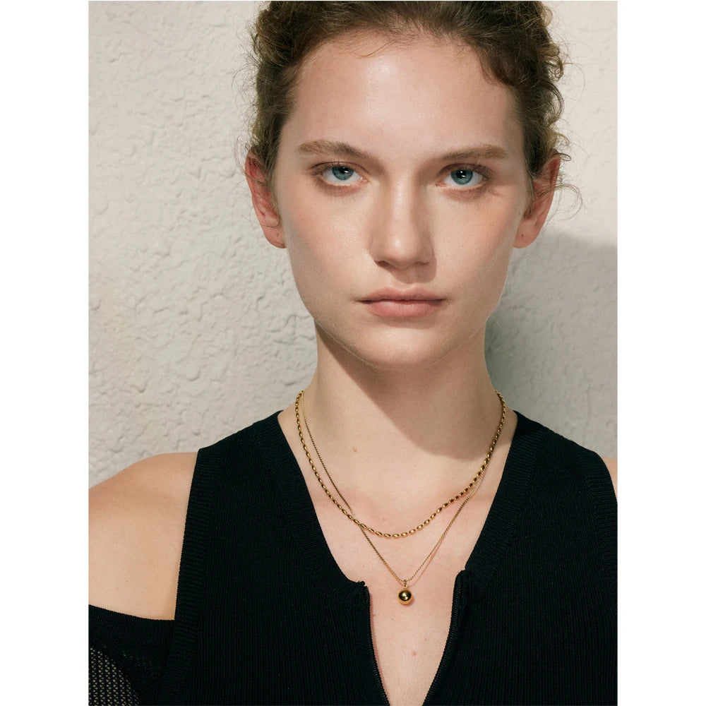 Collier double avec pendentif boule, porté avec un haut noir – Charmhabit