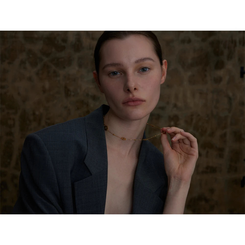 Collier avec petites fleurs, porté, la main près du cou – Charmhabit