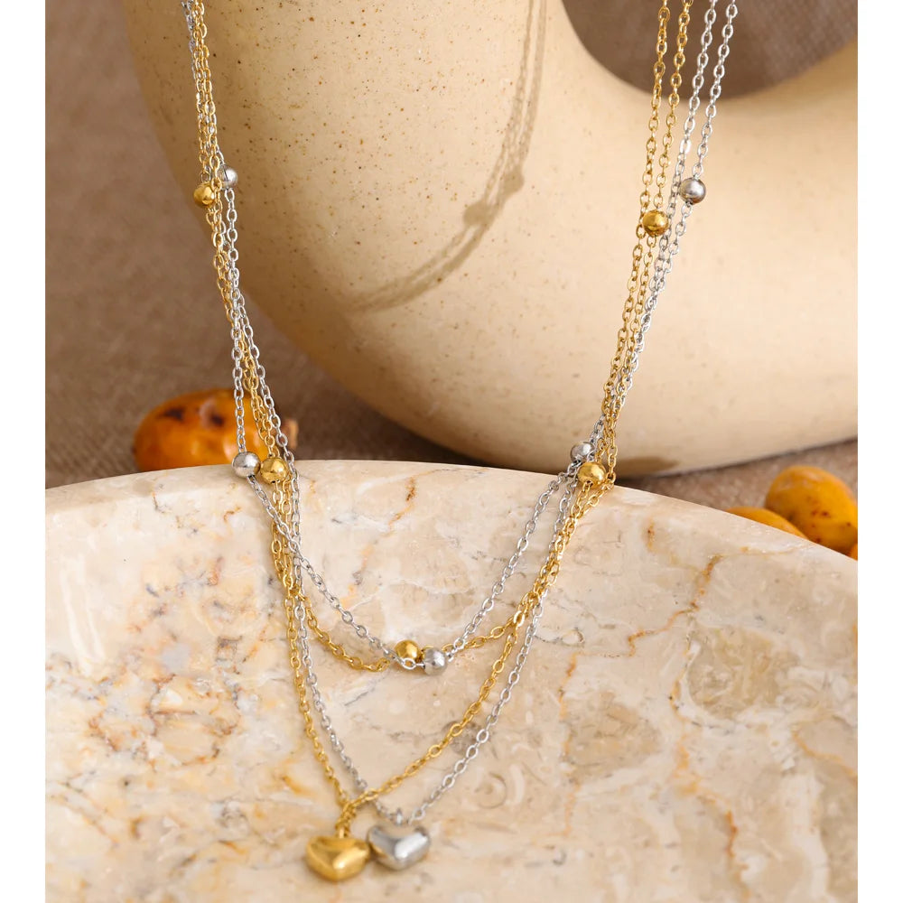 Dubbele ketting met hartjes, goud en zilver, op een keramische vorm – Charmhabit
