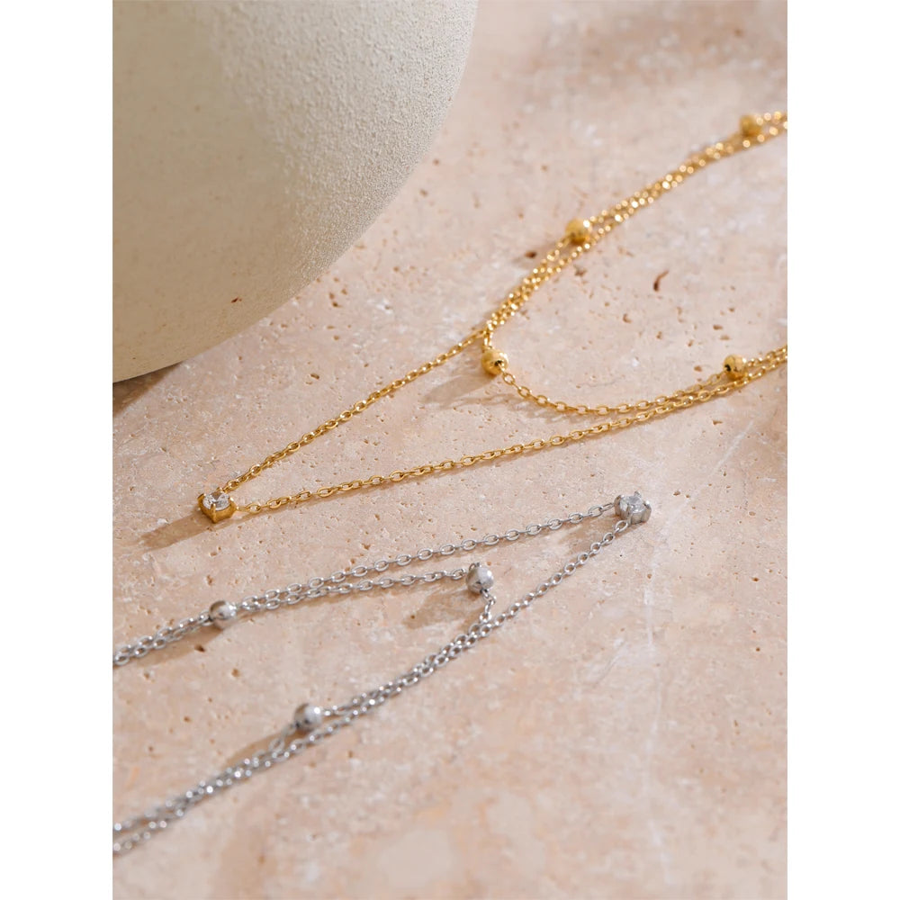 Dubbele ketting met zirkonia, goud en zilver, op een lichte ondergrond – Charmhabit