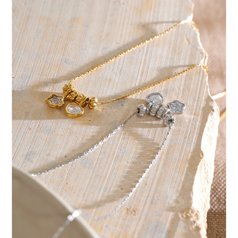 Necklace with heart and star charms, gold and silver tone, close-up on stone – Charmhabit