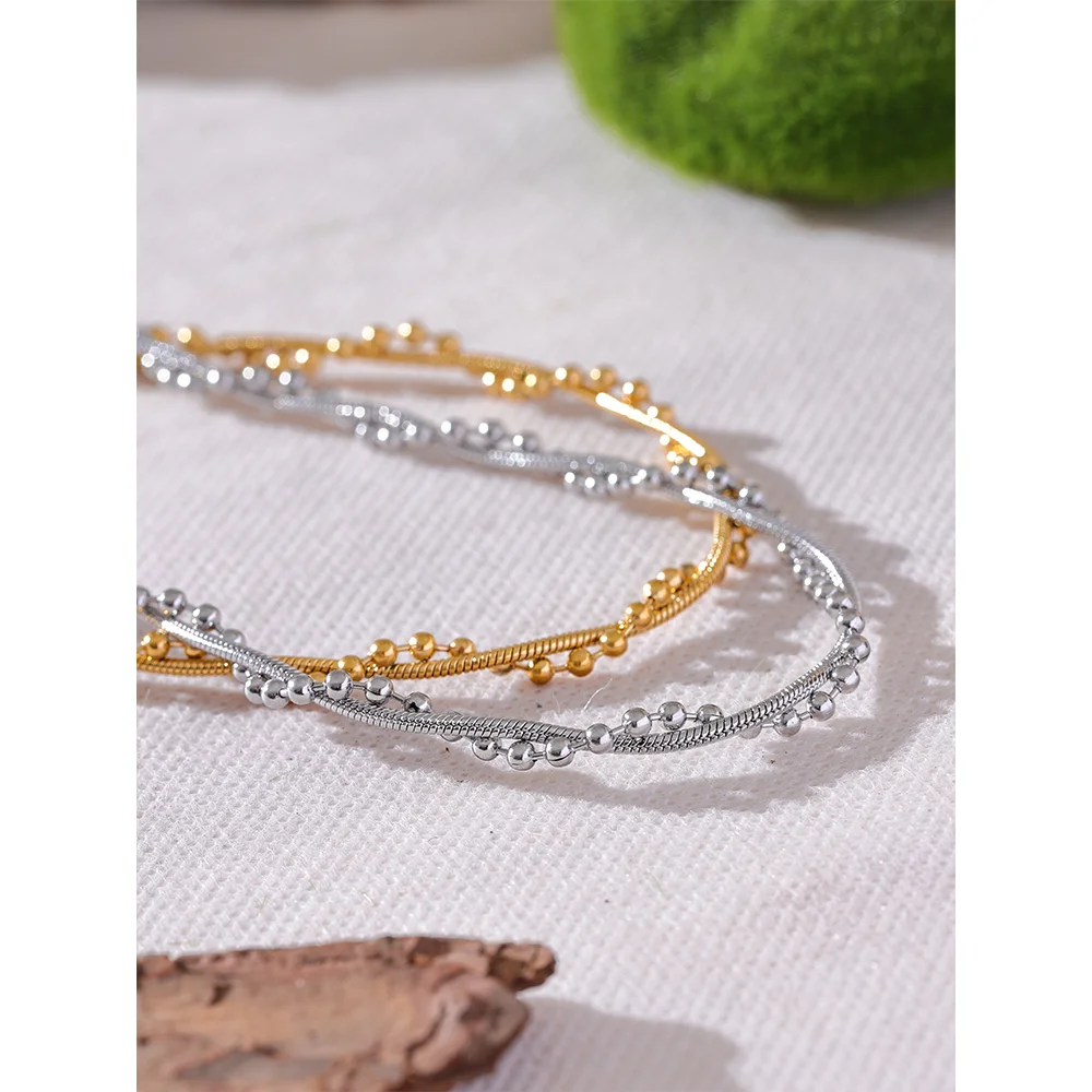 Gedraaide ketting met bolletjes, close-up op een lichte stof met mos – Charmhabit