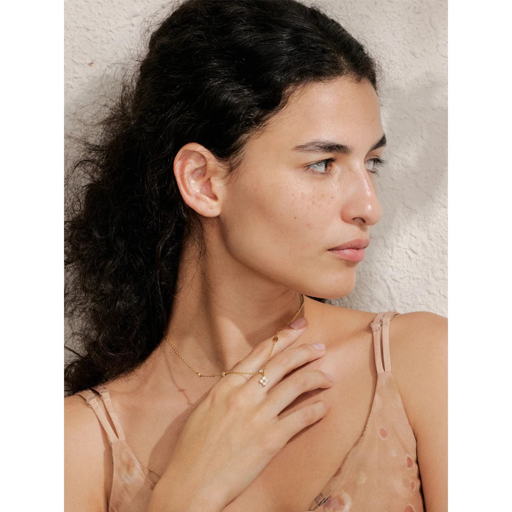 Necklace with cubic zirconia flower pendant, worn with a hand at the neck – Charmhabit