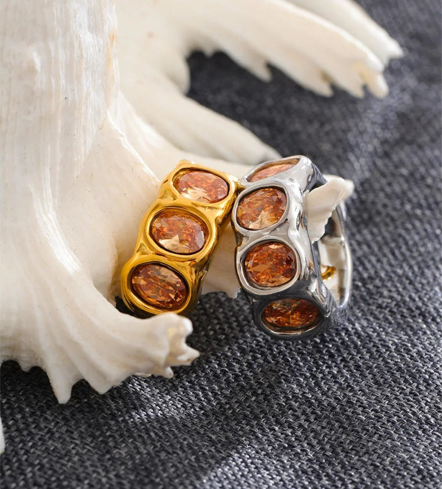 Bague large avec zircons couleur champagne, à côté d'un coquillage – Charmhabit