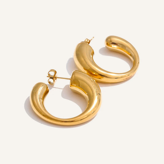 Chunky C-shaped hoop earrings in gold tone, on a light background – Charmhabit