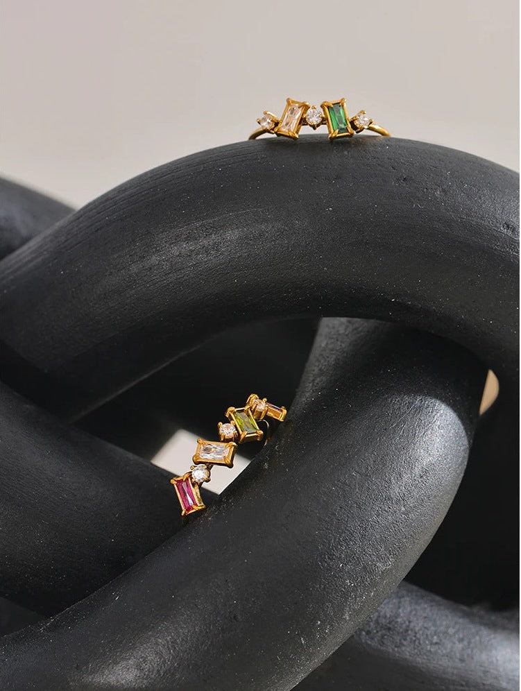 Deux bagues fines avec zircons colorés sur du bois foncé – Charmhabit