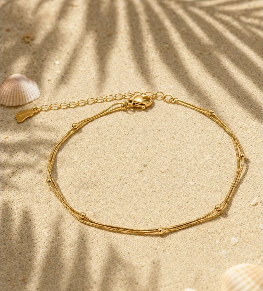Doppeltes Fußkettchen mit Kügelchen auf Sand – Charmhabit
