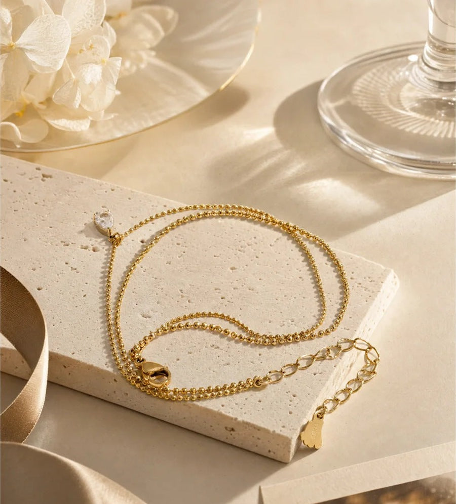 Double anklet with cubic zirconia drop on a light slab – Charmhabit