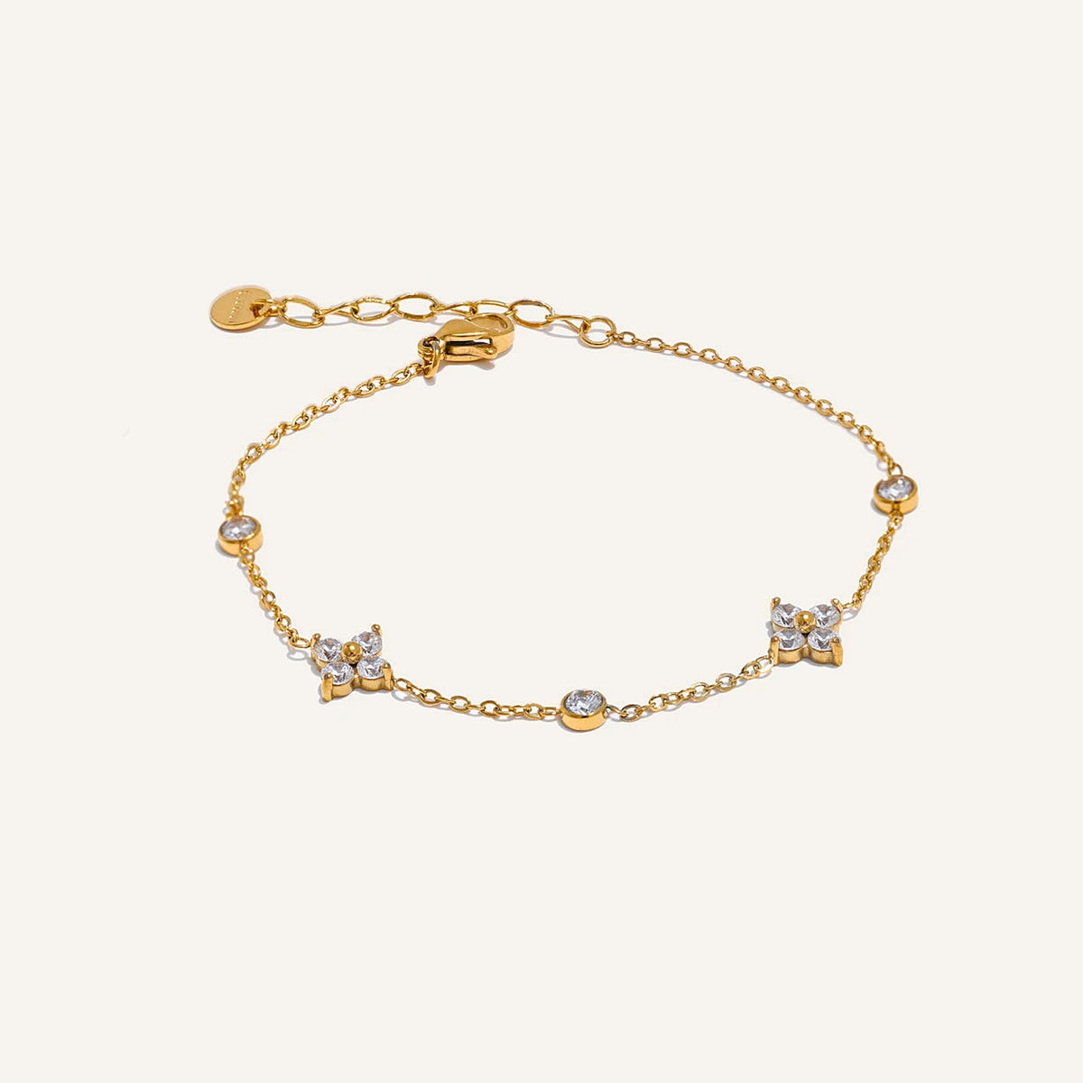 Feines Armband mit Zirkonia-Blüten, goldfarben, auf hellem Hintergrund – Charmhabit
