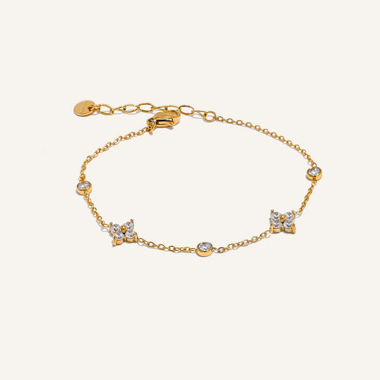 Feines Armband mit Zirkonia-Blüten, goldfarben, auf hellem Hintergrund – Charmhabit