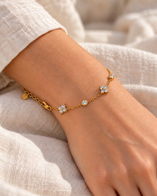 Feines Armband mit Zirkonia-Blüten, goldfarben, am Handgelenk getragen – Charmhabit