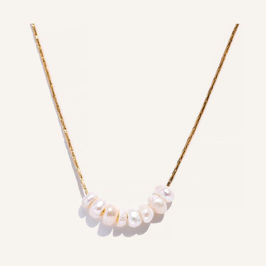 Feine Kette mit Perlen, goldfarben, auf hellem Hintergrund – Charmhabit