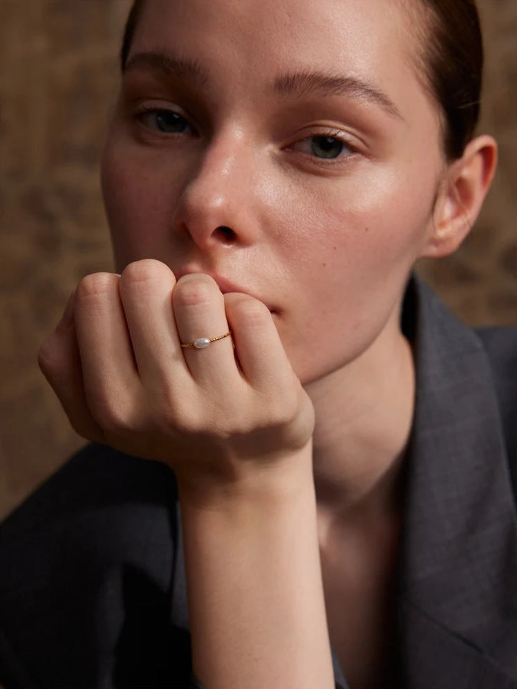 Feiner Perlenring, goldfarben, an der Hand getragen – Charmhabit