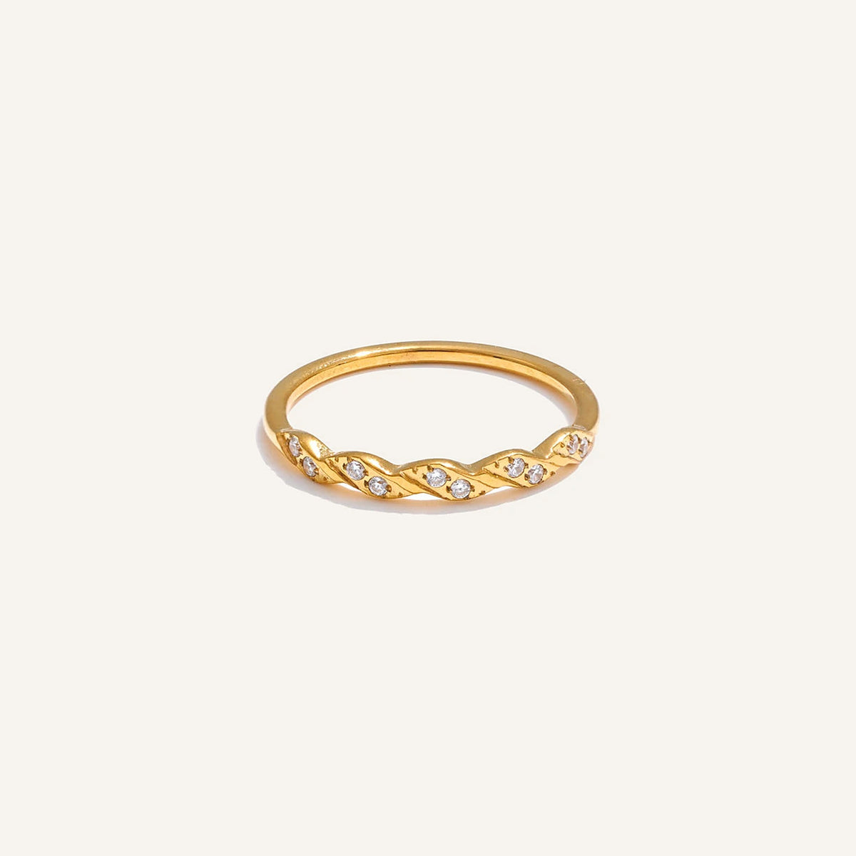 Gedrehter Ring mit Zirkonia, goldfarben, auf hellem Hintergrund – Charmhabit