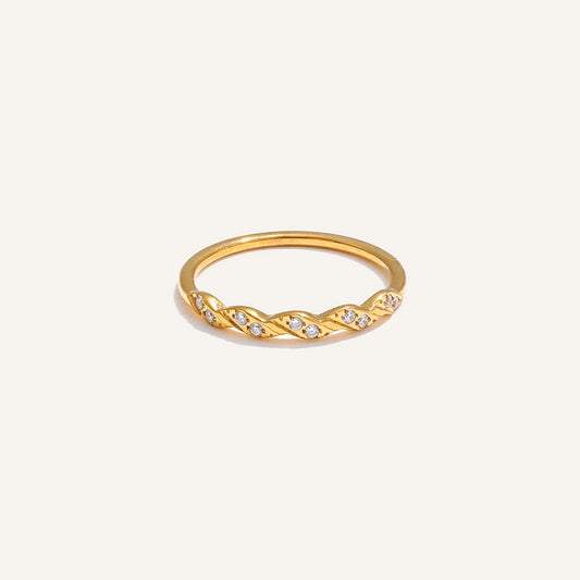 Twisted ring with cubic zirconia, gold tone, on a light background – Charmhabit