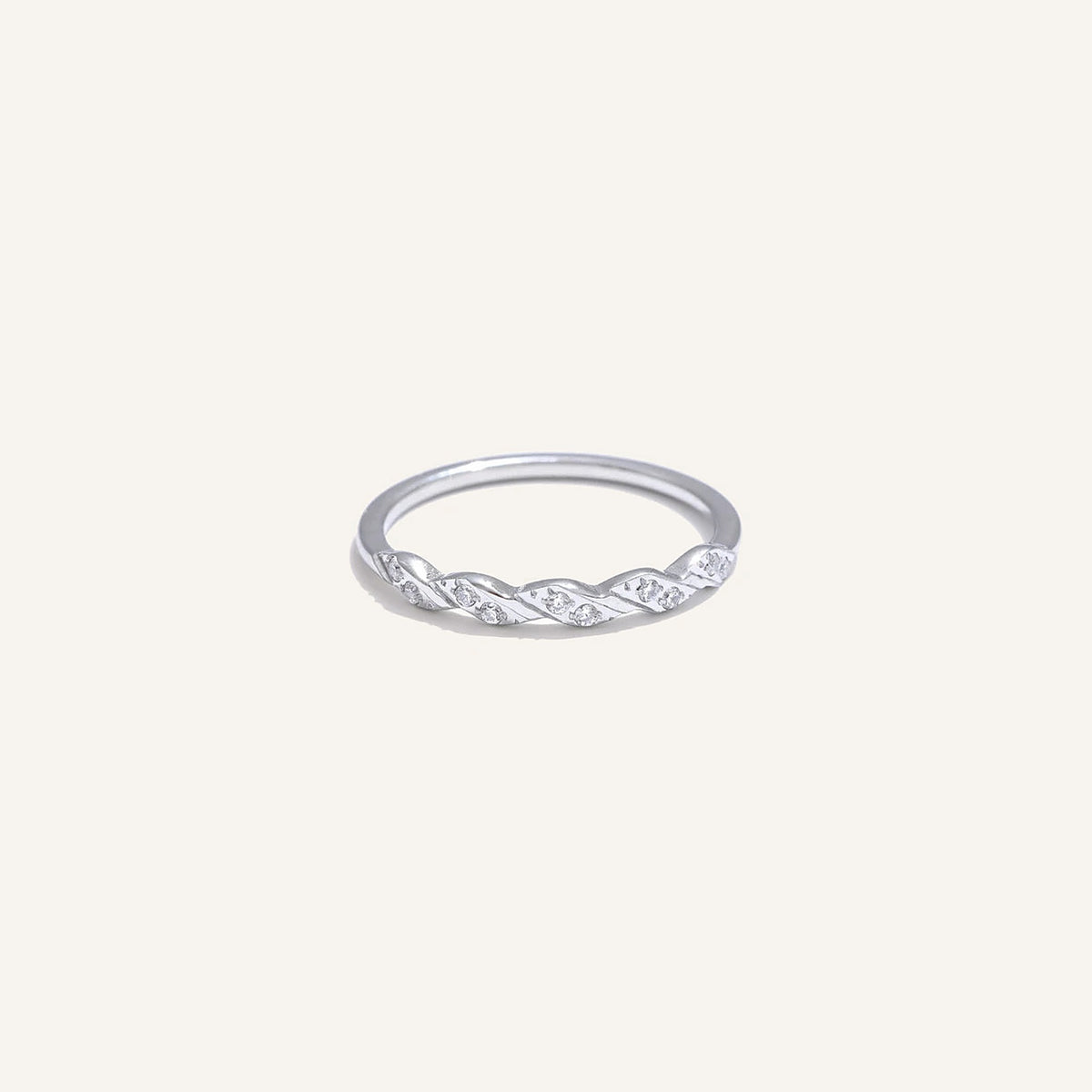 Gedrehter Ring mit Zirkonia, silberfarben, auf hellem Hintergrund – Charmhabit