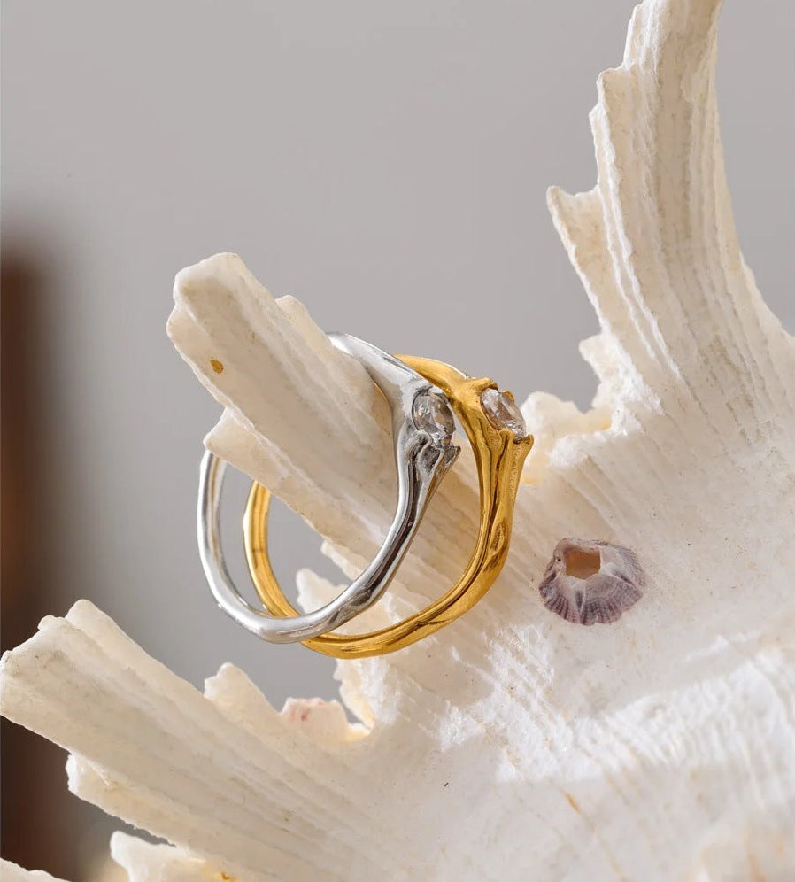 Bague solitaire ondulée avec zircon, en doré et argenté, sur un coquillage – Charmhabit